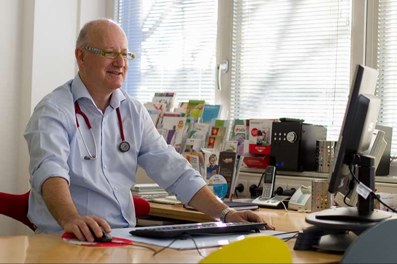 Dr. Georg Maiwald sitzt am Schreibtisch und schaut auf seinen PC.